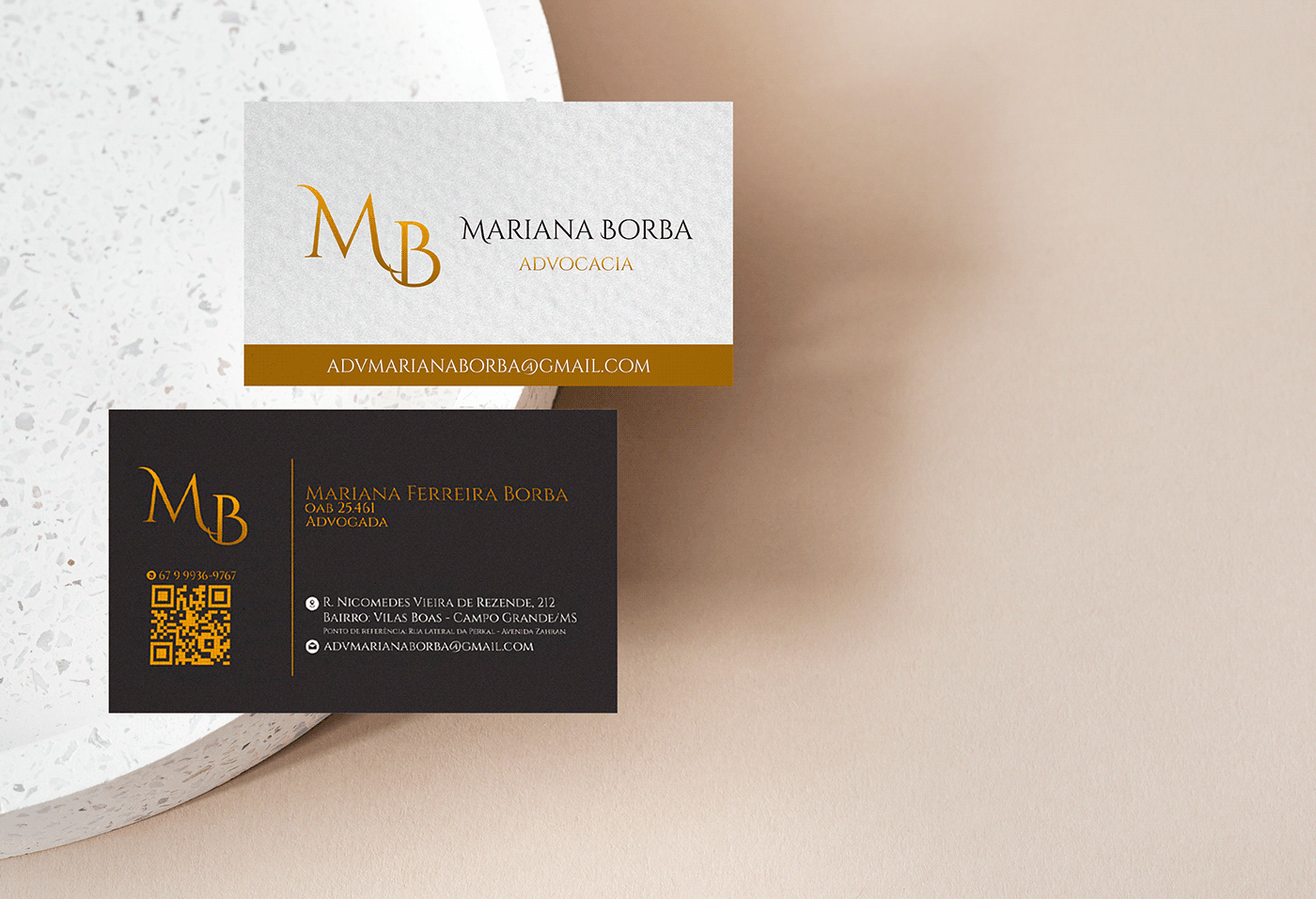 Cartão de visitas da Mariana Borba com logotipo dourão sobre fundo bege